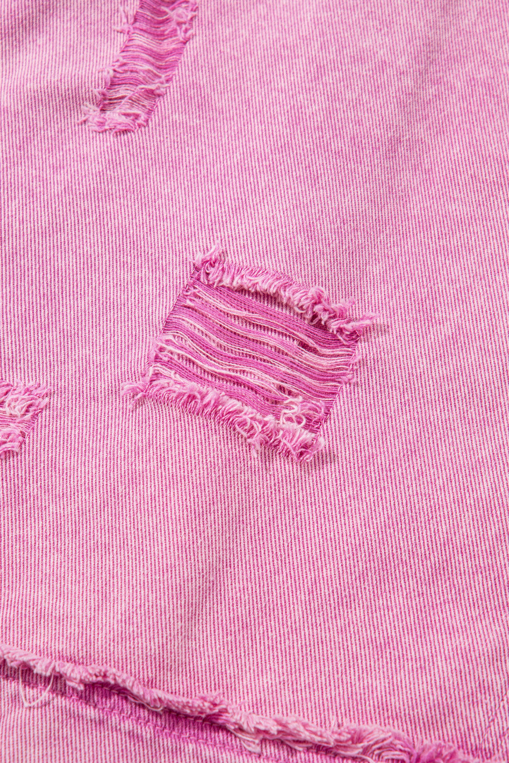Close-up of pink denim fabric with frayed edges